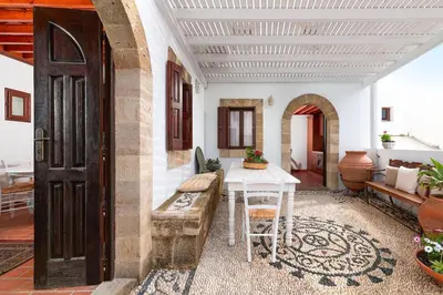 a living room with a table and a couch and a door at Acropolis Lindos House in Líndos