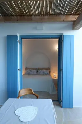 a bedroom with a bed with blue doors and a table at Tilos Villa in Livadia