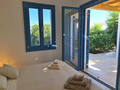 a bedroom with a bed and a large window at Tilos Villa in Livadia