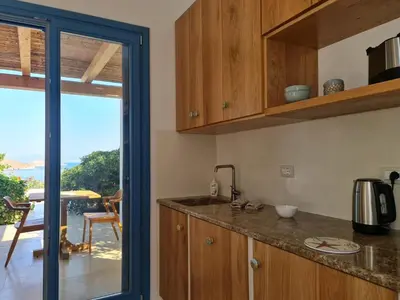 a kitchen with wooden cabinets and a view of the ocean at Tilos Villa in Livadia