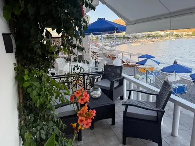 a patio with chairs and tables and umbrellas and the water at VILLA BLANCA in Haraki