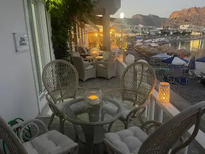 a patio with chairs and a table with a view of the water at VILLA BLANCA in Haraki