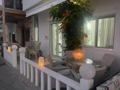 a porch with a table and chairs and windows at VILLA BLANCA in Haraki