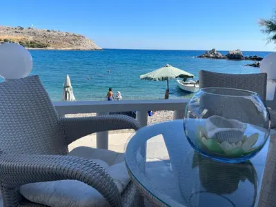 a table with a glass vase on a table with a beach at VILLA BLANCA in Haraki
