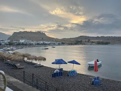 a beach with umbrellas and chairs and boats in the water at VILLA BLANCA in Haraki