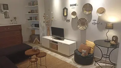 a living room with a desk with a tv and a table at Charming garden apartment in Rhodes Town