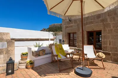 a patio with a table and chairs and an umbrella at Evangelia's Traditional Villa Lindos in Líndos
