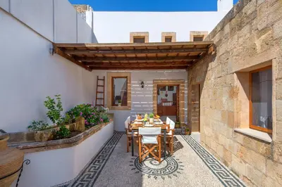 a patio with a table and chairs on a building at Evangelia's Traditional Villa Lindos in Líndos