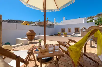 a patio with a table and chairs and an umbrella at Evangelia's Traditional Villa Lindos in Líndos