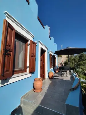a blue building with a patio with an umbrella at Althea Apartments 3 in Halki