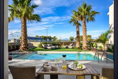 a table with food and drinks on a patio with palm trees at Penélope Beachfront Villa in Kremasti