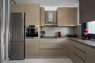 a kitchen with white cabinets and a stainless steel refrigerator at Penélope Beachfront Villa in Kremasti