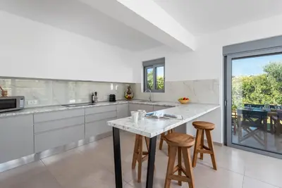 a kitchen with a marble counter top and stools at Villa Heather in Kolimbia