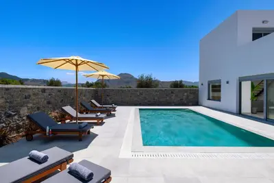 a swimming pool with chairs and an umbrella at Villa Heather in Kolimbia