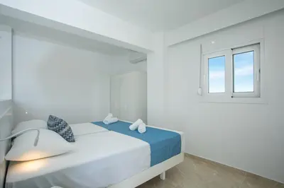 a white bedroom with a bed and a window at VOULA APARTMENTS in Faliraki