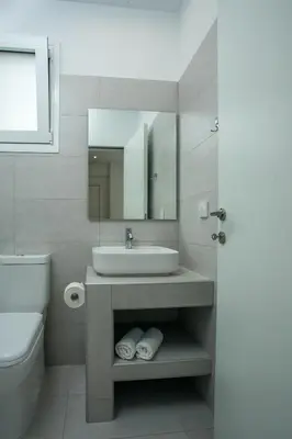 a bathroom with a sink and a toilet and a mirror at VOULA APARTMENTS in Faliraki