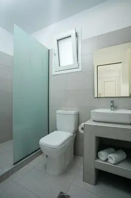 a bathroom with a toilet and a sink and a mirror at VOULA APARTMENTS in Faliraki