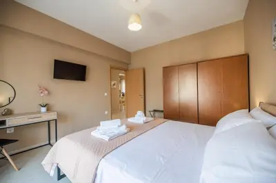 a bedroom with a large white bed and a desk at Katerina's House in Afantou