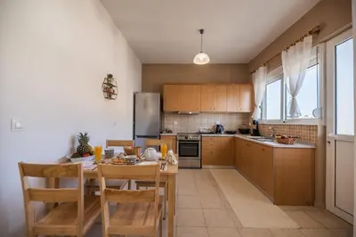a kitchen with wooden cabinets and a table with chairs at Katerina's House in Afantou