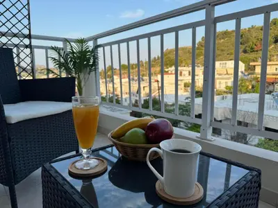 a glass table with a drink and a basket of fruit on a balcony at Katerina's House in Afantou