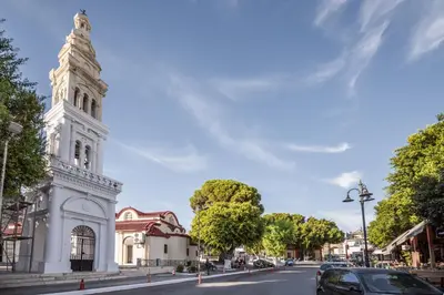a white building with a clock tower on a street at Katerina's House in Afantou