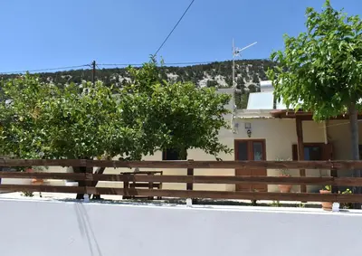 a fence and trees in front of a house at Lithos House in Monólithos
