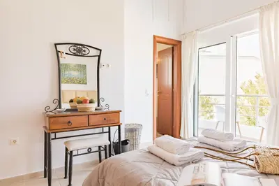 a bedroom with two beds and a desk with a mirror at Villa Thea in Afantou