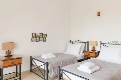 a room with two beds and two tables with lamps at Villa Thea in Afantou