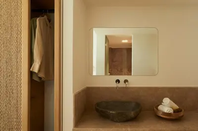 a bathroom with a stone sink and a mirror at Absolute Kiotari Resort in Kiotari