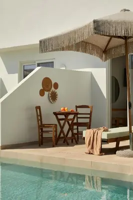 a pool with a table and chairs and an umbrella at Absolute Kiotari Resort in Kiotari
