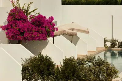 a white building with purple flowers and a swimming pool at Absolute Kiotari Resort in Kiotari