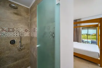 a bathroom with a shower and a bed in a room at Absolute Kiotari Resort in Kiotari