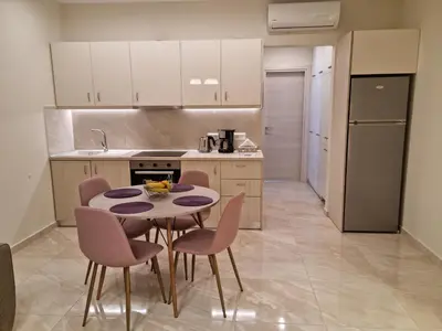 a kitchen with a table and chairs in a room at Ma Maison Rose in Kremasti