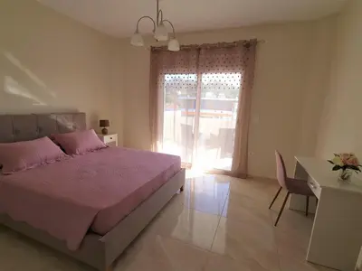 a bedroom with a bed and a desk and a window at Ma Maison Rose in Kremasti