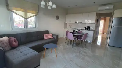 a living room with a couch and a table and a kitchen at Ma Maison Rose in Kremasti