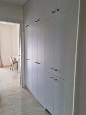 a room with white cabinets and a table with a chair at Ma Maison Rose in Kremasti