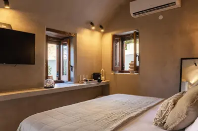a bedroom with a bed with a television and windows at EliteDIMension Chalki in Halki