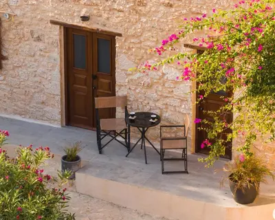 two chairs and a table in front of a building with flowers at EliteDIMension Chalki in Halki