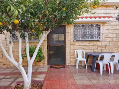 an orange tree in front of a house with a table and chairs at Villa Kavalino in Kolimbia