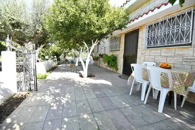 a patio with white chairs and a table and trees at Villa Kavalino in Kolimbia