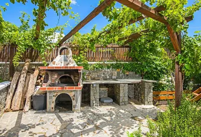 an outdoor pizza oven in a yard with a fence at Villa Kiotari Alia in Kiotari