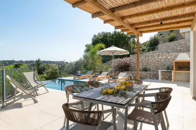 a patio with a table and chairs and a pool at Massari Hills Luxury Living in Malona Village
