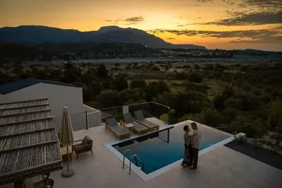 a couple standing on the balcony of a house with a pool at Massari Hills Luxury Living in Malona Village
