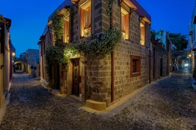 an old brick building with ivy on a street at night at Mythic Spa Villa in Rhodes Town