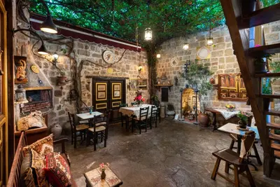a restaurant with tables and chairs in a stone wall at Mythic Spa Villa in Rhodes Town