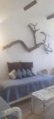 a bedroom with a blue bed with a tree branch on the wall at ALONI G&A Archaggelos in Archangelos