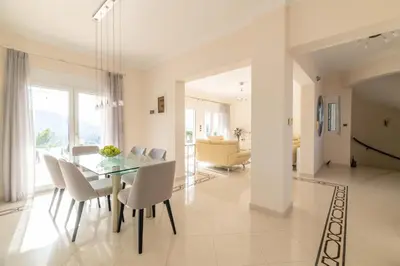 a dining room with a glass table and white chairs at Villa Kamos in Archangelos