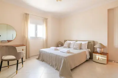 a bedroom with a bed and a chair and a mirror at Villa Kamos in Archangelos