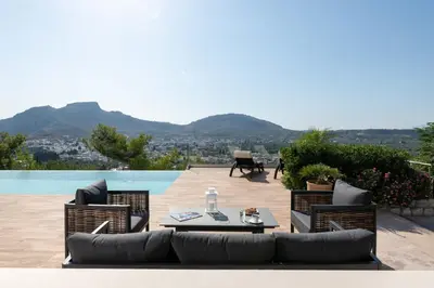 a patio with a table and chairs and a pool at Villa Kamos in Archangelos