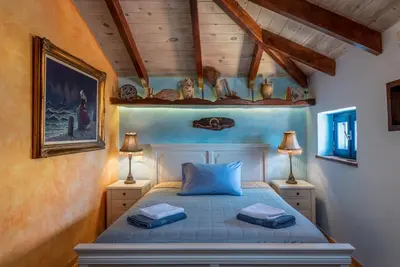 a bedroom with a bed with blue sheets and two lamps at Chalki Jewel in Halki